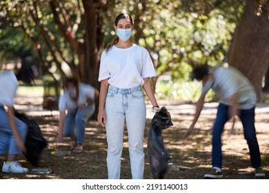 Volunteer Help Of Covid Cleaning Community Group Working Together Outdoors. Portrait Of A Young Female Worker Doing Nature And Forest Clean Up Of Plastic Garbage Outside To Be Green For The Future