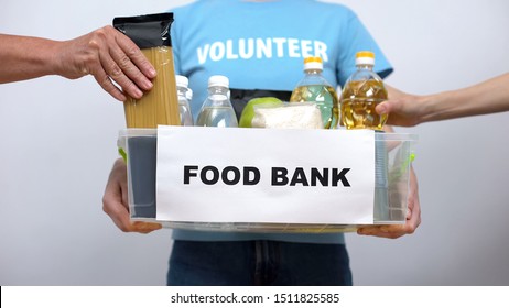 Volunteer Holding Food Bank Container, Hands Putting Provision In Box, Help