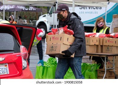 A Volunteer Loads Food Into The Trunk Of A Vehicle During A Drive Thru Food Distribution By The Los Angeles Regional Food Bank At Exposition Park On Saturday, Jan. 23, 2021, In Los Angeles.