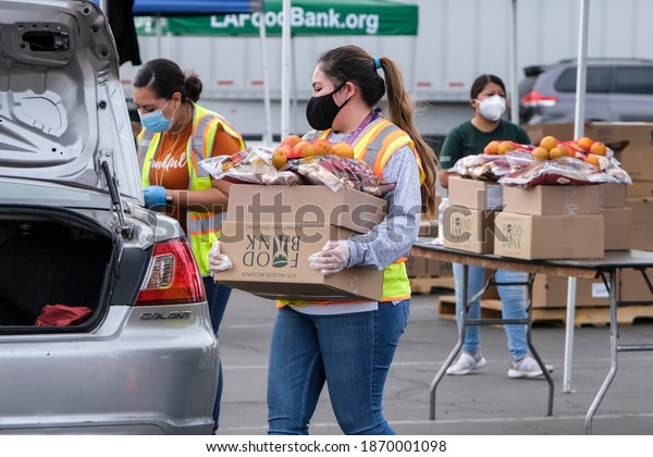 A volunteer loads food\
into the trunk of a vehicle during a drive thru food distribution\
by the Los Angeles Regional Food Bank in Glendora, Calif. Dce. 8,\
2020.
