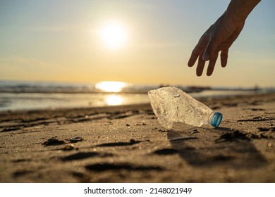 Volunteer man and plastic bottle, clean up day, collecting waste on sea beach, pollution and recycling concept - Shutterstock ID 2148021949