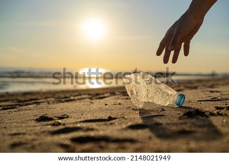 Volunteer man and plastic bottle, clean up day, collecting waste on sea beach, pollution and recycling concept