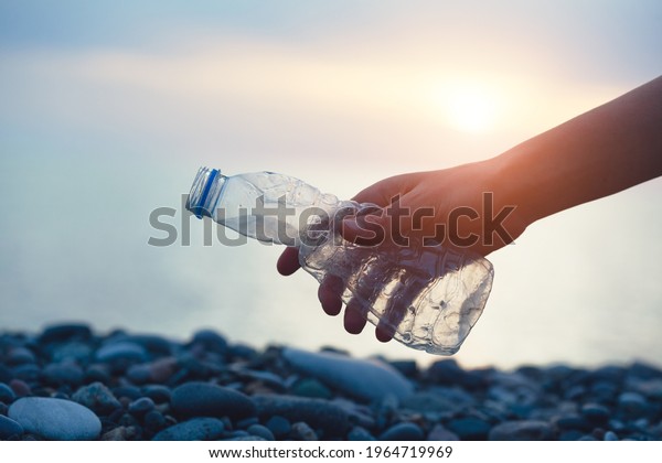 Volunteer man and\
plastic bottle, clean up day, collecting waste on sea beach,\
pollution and recycling\
concept