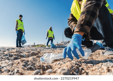 Volunteer man's hand with gloves picking up plastic rubbish from the beach to clean the sand together with his fellow activists Recycling concept. High quality photo - Powered by Shutterstock