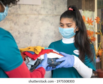 Volunteer With Medical Face Mask And Hand Gloves Received Donation As Cloth - Concept Of Charity, Social Service And Community Help During Coronavirus Covid-19 Pandemic Lockdown.