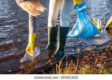 Volunteer picking up plastic bottle from polluted lake or river. Environmental damage. Water pollution with plastic garbage - Powered by Shutterstock