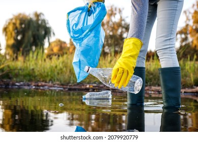 Volunteer picking up plastic bottle from polluted lake or river. Water pollution with plastic garbage. Environmental damage - Powered by Shutterstock