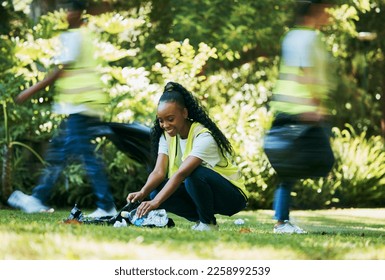 Volunteer, plastic and black woman cleaning park as community service for recycling and pollution. Ngo person happy to help group with bottle, dirt and trash bag outdoor in green nature environment - Powered by Shutterstock