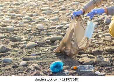 Volunteer saving sea from trash. Man cleaning on the beach trowing out mask. - Powered by Shutterstock