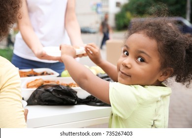 Volunteer sharing food with African child outdoors