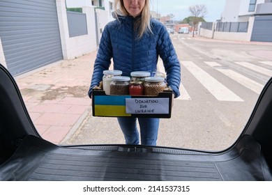 Volunteer Taking A Box Out Of The Car With Donation Food For Ukrainian Refugees Suffering From The War.