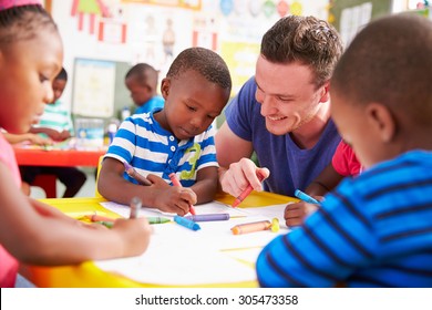 Volunteer teacher helping a class of preschool kids drawing