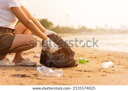 Volunteer woman picking plastic bottle into trash plastic bag black for cleaning the beach, female clean up garbage, Ecology concept and World Environment Day, Save earth concept