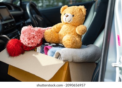 Volunteer Woman Provide Clothing Donation Box With Used Clothes And Doll In Car To Support Help For Refugee, Homeless Or Poor People In The World.