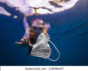 Volunteer woman scuba divers are exploring underwater and cleaning up the ocean. Catch a disposable masks outbreak trash on the blue water. Trash in the beach threatening the health of oceans. - Powered by Shutterstock