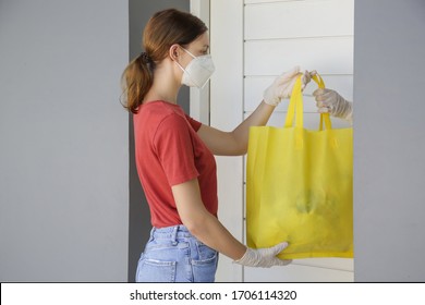 Volunteer women brings a bag with food and another unessesary groceries for persons in need. Delivery to the door. Food delivery services during coronavirus pandemic.	
