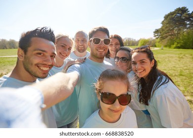 volunteering, charity and people concept - group of happy volunteers taking selfie by smartphone in park - Powered by Shutterstock