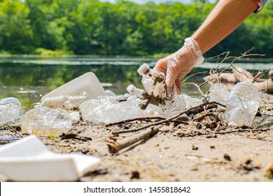 Volunteers Cleaning Garbage Near River. Women Picking Up A Bottle Plastic In The Lake, Pollution And Environment. Ecology Concept