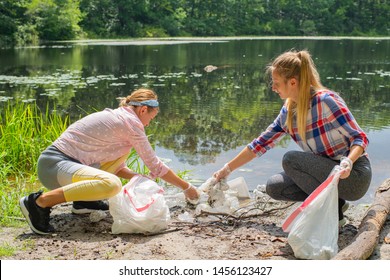 Volunteers Cleaning Garbage Near River. Women Picking Up A Bottle Plastic In The Lake, Pollution And Environment. Ecology Concept