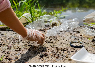 Volunteers Cleaning Garbage Near River. Women Picking Up A Bottle Plastic In The Lake, Pollution And Environment. Ecology Concept