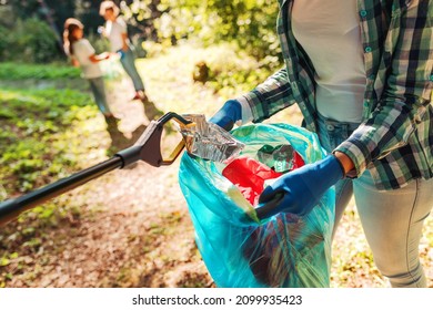 Freiwillige, die den Park aufräumen, eine Frau Mülltüte in eine Mülltüte legen und einige Kinder helfen ihr, Umweltschutzkonzept
