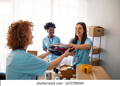 Volunteers Collecting Food Donations In Warehouse. Team of volunteers holding donations boxes in a large warehouse. Volunteers putting clothes in donation boxes, social worker making notes charity - Powered by Shutterstock