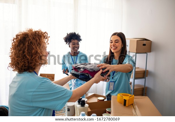 Volunteers Collecting Food Donations In\
Warehouse. Team of volunteers holding donations boxes in a large\
warehouse. Volunteers putting clothes in donation boxes, social\
worker making notes\
charity