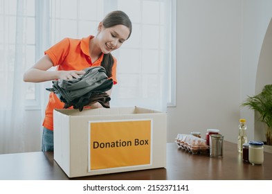 Volunteers Collecting Food garment donations box In home.Asian woman holding donations boxes in a large warehouse.Thai female putting clothes in charity boxes. joy of sharing to poor and afflicted. - Shutterstock ID 2152371141