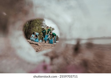 Volunteers are diligently collecting trash along a riverbank, contributing to environmental cleanup and demonstrating social responsibility - Powered by Shutterstock