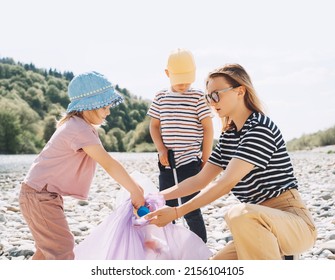 Volunteers Family Collecting Plastic Waste Trash On River Beach. People Help To Keep Nature Clean Up And Pick Up Garbage. Woman And Kids Helping Clean Up Outdoor Area From Rubbish.