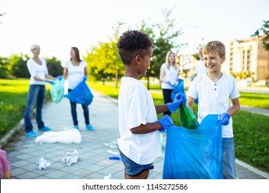 Volunteers with garbage bags cleaning up garbage outdoors - ecology concept.