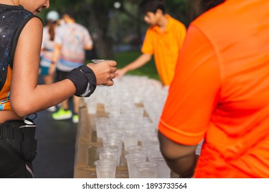 Volunteers Give Out Glasses Of Water To Athletes Running A Marathon