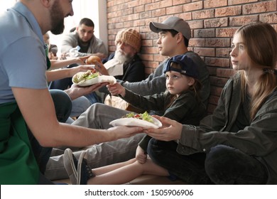 Volunteers Giving Food To Poor People Indoors