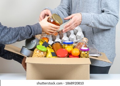 Volunteers Hands Putting Grocery Products, Foodstuff To Food Donations Box