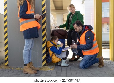 Volunteers Helping Ukrainian Refugee Family At Train Station, Filling Forms.