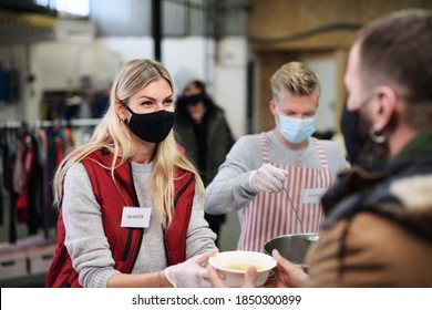 Volunteers serving hot soup for homeless in community charity donation center, coronavirus concept. - Shutterstock ID 1850300899