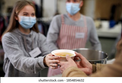 Freiwillige, die heiße Suppe für Obdachlose in gemeinnützigen Spendenzentrum, Coronavirus-Konzept.