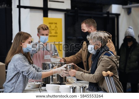 Volunteers serving hot soup for homeless in community charity donation center, coronavirus concept.