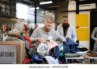 Volunteers sorting out donated clothes in community charity donation center. - Powered by Shutterstock