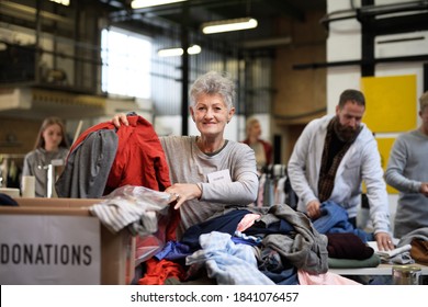 Volunteers Sorting Out Donated Clothes In Community Charity Donation Center.