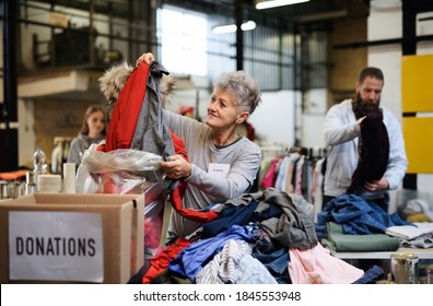 Volunteers sorting out donated clothes in community charity donation center, coronavirus concept. - Powered by Shutterstock