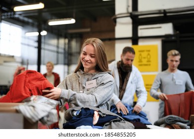 Volunteers sorting out donated clothes in community charity donation center. - Powered by Shutterstock