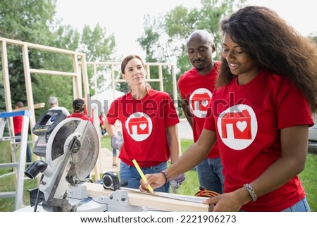 Volunteers at table saw near construction frame