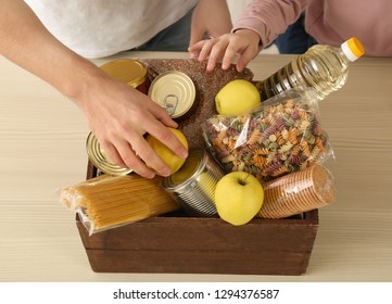 Volunteers Taking Food Out Of Donation Box On Table, Closeup