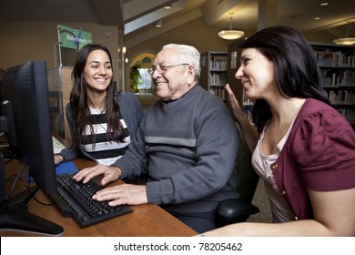 Volunteers teaching a senior how to use a computer