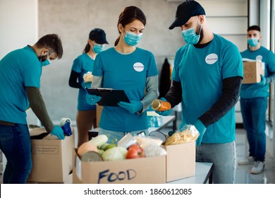 Volunteers wearing face masks while working in charitable foundation and packing donation boxes for food bank. 