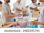 Volunteers working at humanitarian aid center. Diverse Caucasian and African American men and women collect food and clothes to take them to people in refugee shelters. Help, charity, donation concept