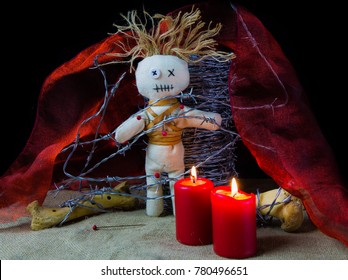 A Voodoo Altar With Doll, Red Candles And Barbed Wire In Front Of Black Background