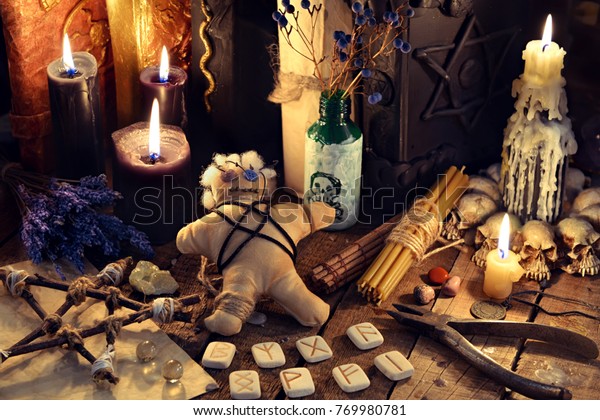 Voodoo doll, black candles, pentagram
and old books on witch table. Occult, esoteric, divination and
wicca concept. Mystic, voodoo and vintage background
