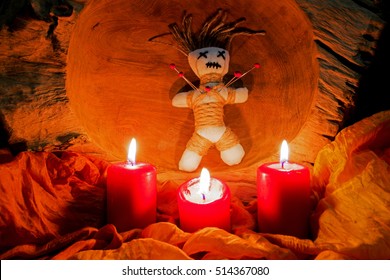 A Voodoo Doll With Needles Stands On An Altar With Candles
